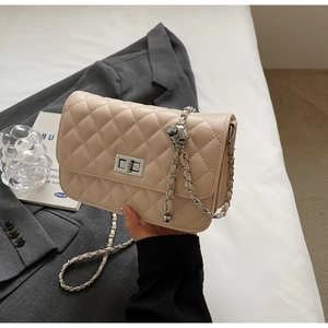Detailansicht der beigen Stepptasche mit silberner Kette und Metall-Drehverschluss