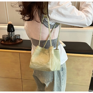 Primo piano della borsa a tracolla verde chiaro plissettata con finitura lucida e manici