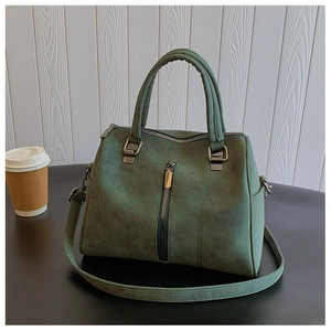 Detail of dark green vintage tote bag with vertical zippers and dual handles on a wooden background