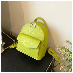 Detail of lime green mini backpack featuring lychee texture and silver double zippers