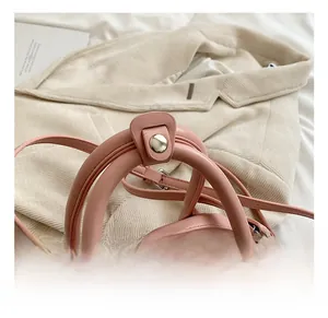 Detail view of pink leather handbag featuring a smooth rounded handle and silver zipper