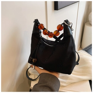 Detail of black baguette bag featuring amber resin bead handle and star embroidery