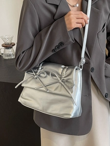 Silver metallic puffer tote bag with ribbon details shown as a casual crossbody bag