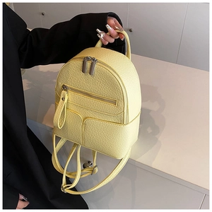 Close-up of pale yellow pebbled leather mini backpack with silver zippers and hardware