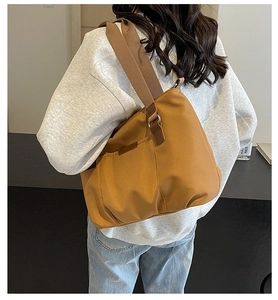 Close-up of brown nylon tote bag with wide shoulder strap and functional side pocket