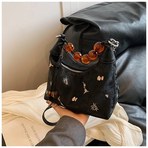 Detailed embroidery on black fabric with vintage amber bead handle on Boston bag