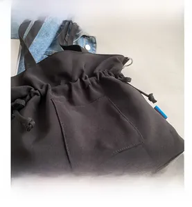 Vue détaillée du sac cabas en toile noire avec cordon et poche frontale