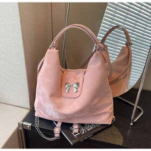 Détail d'un sac cabas en daim rose avec une boucle en métal argenté et une fine chaîne