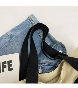 Close-up of beige canvas tote bag showing durable black woven shoulder strap stitching