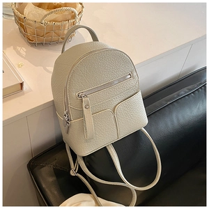 Detail of mini cream-colored backpack in lychee-textured leather on a white surface