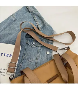 Detail of adjustable long shoulder strap and silver metal buckle on brown canvas tote bag