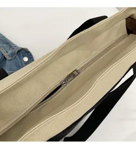 Close-up of a silver metal zipper on a large canvas tote bag with contrast webbing straps