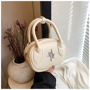 Detailed view of cream PU leather handbag featuring silver star metal hardware and dual handles