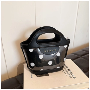 Detailed view of polka dot PVC tote bag with MUDUO brand logo and black leather trim