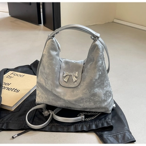 Sac fourre-tout argenté avec boucle nœud métallique sur veste en cuir noir et magazine