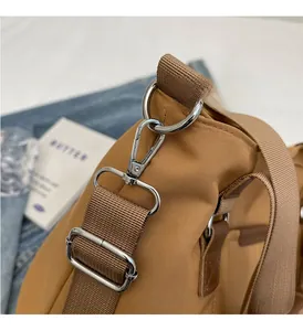 Close-up of polished silver hardware and durable khaki nylon strap on a tote bag