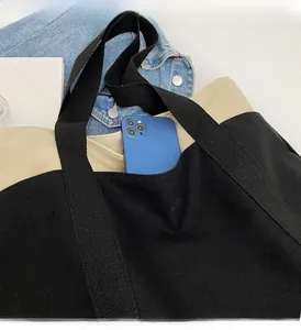 Detailed view of canvas tote bag with contrast front pocket holding a smartphone