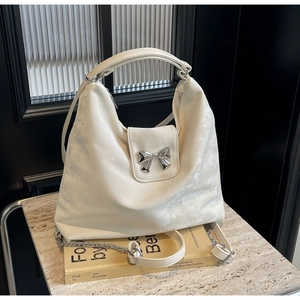 Détail du sac fourre-tout crème avec nœud argenté et bandoulière chaîne amovible