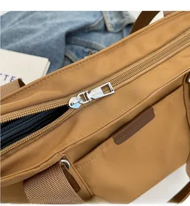 Detailed macro of smooth silver metal zipper on brown nylon waterproof shoulder bag