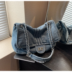 Détail du sac fourre-tout en jean bleu avec bandoulière chaîne et fermoir pivotant