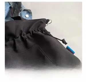 Détail du sac cabas en toile noire avec cordon de serrage et anneaux métalliques argentés