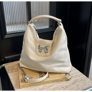 Vue détaillée du sac hobo crème avec nœud en métal argenté et texture cuir premium