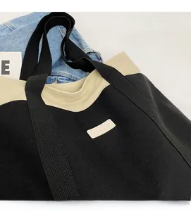 Detail of the high-capacity canvas tote bag featuring black and beige contrast stitching