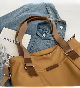 Detail of the reinforced caramel nylon tote handle with durable leather grip and metal rings