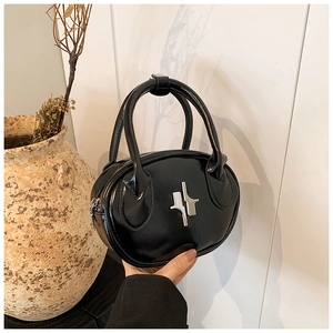 Close-up of a glossy black oval handbag with silver metal logo and zip closure