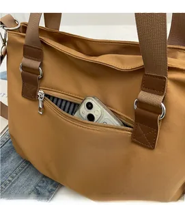 Detail of khaki nylon tote bag showing front zipper pocket and blue striped lining
