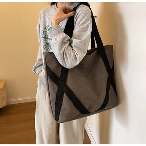 Detail of large canvas tote bag with black cross straps and dark grey minimalist finish