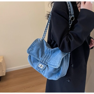 Détail du sac cabas en denim bleu avec fermoir rotatif argenté et bandoulière en chaîne