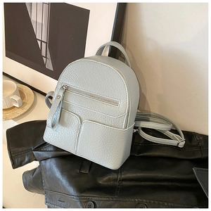 Detail of light blue mini backpack with lychee texture placed on a black leather jacket