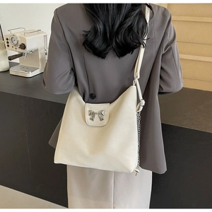 Détail d'un grand sac cabas crème avec ornement nœud argenté et bandoulière en chaîne