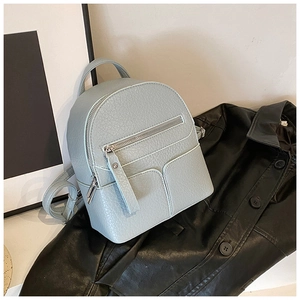 Close-up of light blue mini leather backpack featuring premium lychee texture on black jacket