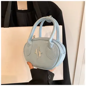 Close-up of light blue oval handbag with silver metal logo and premium leather texture