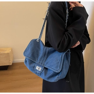 Vue détaillée du sac à bandoulière en denim bleu avec fermoir rotatif argenté et chaîne