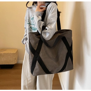 Detail view of large charcoal grey canvas tote bag with black cross webbing on shoulder