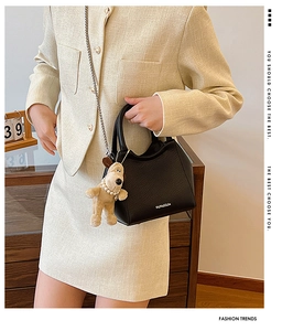 Détail du sac seau en cuir noir avec bandoulière chaîne et breloque chiot en peluche