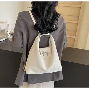 Détails du sac à dos en velours beige avec nœud en métal argenté et accents de chaîne fins