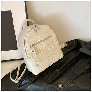Close-up of mini cream leather backpack with lychee texture and silver zippers
