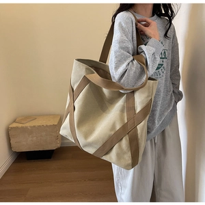 Detail of contrast canvas tote bag featuring brown woven straps and large capacity