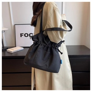 Détail d'un sac seau en toile noire avec cordon de serrage et poche sur le modèle