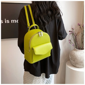 Close-up of neon green mini backpack with lychee texture and slim leather straps