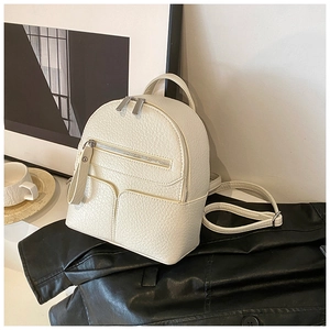 Close-up of a mini cream leather backpack with pebbled texture and silver zippers