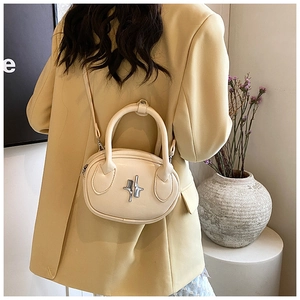 Detail of a chic cream oval crossbody bag with star metal ornament worn by a model