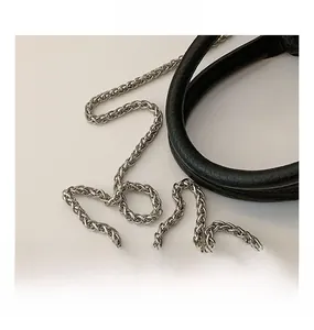 Détail de la bandoulière en cuir noir et de la chaîne en métal argenté du sac seau