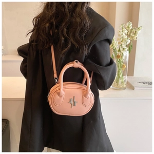 Detail of pink oval crossbody bag with silver hardware on a black blazer background
