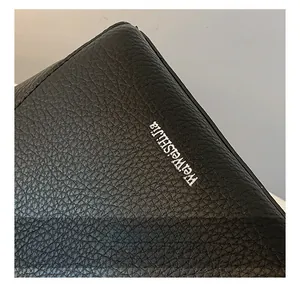Gros plan du sac seau en cuir noir à grain lychee avec détails métalliques argentés