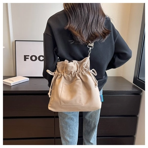 Détail du sac seau beige à cordon en cuir souple avec étiquette de la marque Studio